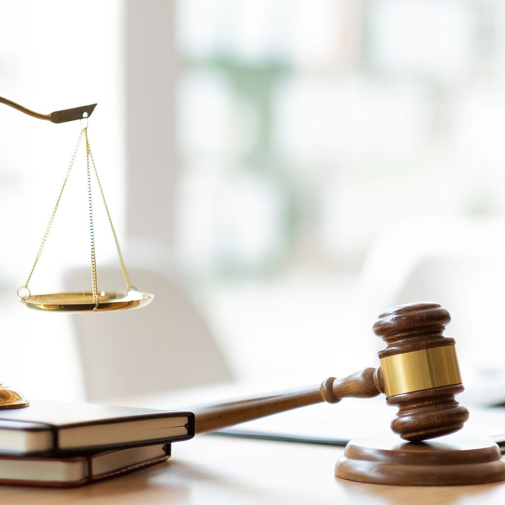 A close-up of a wooden gavel and a brass scale on a desk, symbolizing justice and the practice of immigration law.